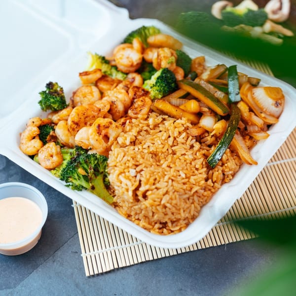 Tokyo Express Grill's shrimp hibachi with fried rice, broccoli, zucchini, and onions in a takeout container.